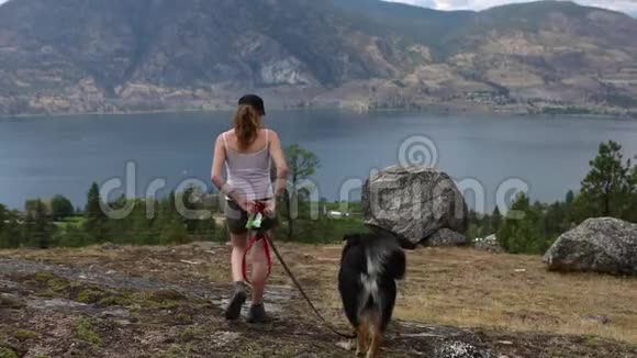 女人和狗在山湖边散步视频的预览图