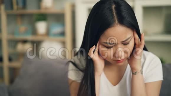不高兴的亚洲女学生感到头痛并试图释放疼痛按摩她的头触摸视频的预览图