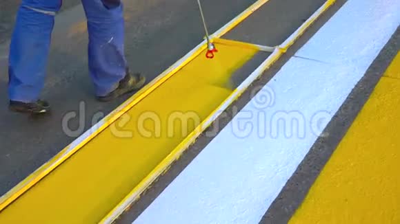 道路标记油漆道路线路工人在人行横道上画白色和黄色的人行横道线视频的预览图