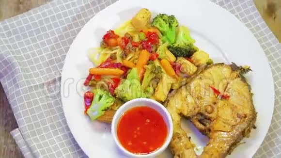 一盘带蔬菜和亚洲酱的鱼和意大利面围绕着一张格子餐巾旋转视频的预览图