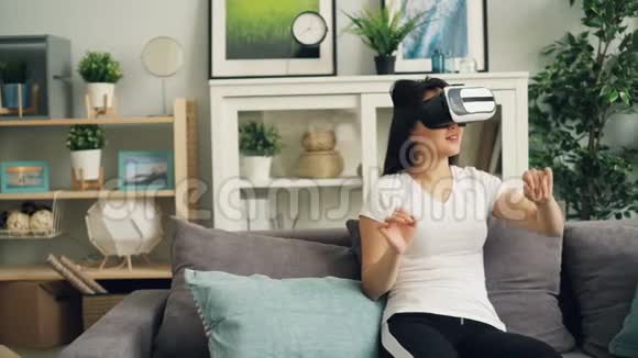 美丽的黑发黑发美女正在玩虚拟现实眼镜移动头和手戴耳机女孩是视频的预览图