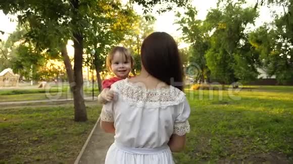 小女儿在妈妈手里幸福的一家人走在夏日公园里慢动作视频的预览图