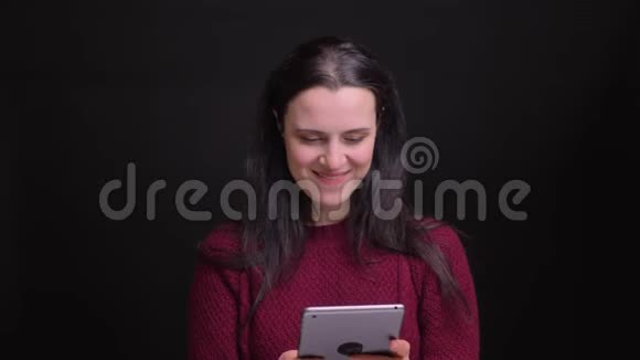用平板电脑特写白种人黑发年轻女性的肖像兴奋地笑着视频的预览图