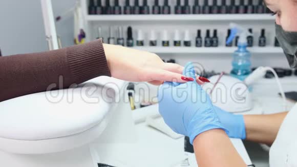 医生在美容院给顾客的指甲涂上红色的凝胶视频的预览图