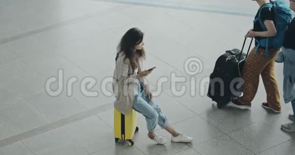 年轻漂亮的女人坐在机场用笔记本电脑打印耳机女游客自由职业者视频的预览图