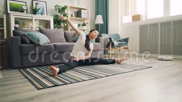 苗条的亚洲女学生正在家里做瑜伽在地毯上坐在地板上做伸展运动视频的预览图