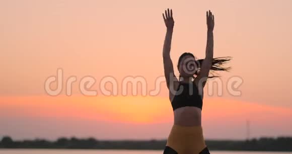 女人在海滩上做运动一个黑发女子教练穿着运动短上衣和健身裤做运动视频的预览图