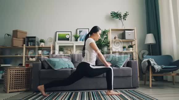 灵活的亚洲女孩在家里做伸展运动独自练习瑜伽姿势以改善她的健康和关心视频的预览图
