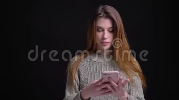 年轻漂亮的白种人女性的特写肖像随意地在电话上发短信背景与黑色隔离视频的预览图