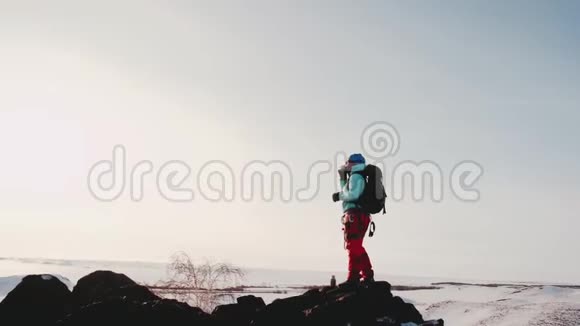 登山者站在寒冷的山巅上带着一杯热饮料温暖的景色视频的预览图