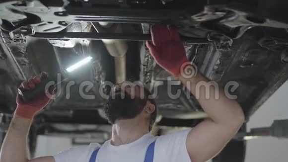 汽车修理工在维修服务站用举升汽车灯检查汽车内的悬挂或刹车视频的预览图
