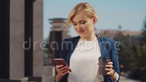金发白种人的外表是清晨在街上喝着咖啡和她的朋友发短信视频的预览图
