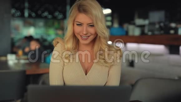性感的女人坐在咖啡馆里用手提电脑听音乐视频的预览图