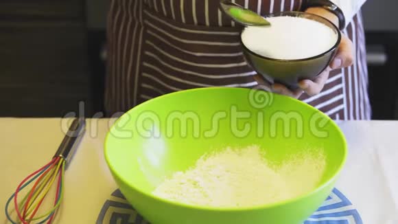 在家庭厨房的绿色碗里一只雌性手的特写将糖加入面粉中烹饪煎饼视频的预览图