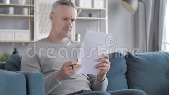 灰色头发人阅读协议坐沙发视频的预览图