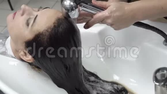 一个女人在美容院做了染色后洗了头把头发上的棕色油漆洗掉视频的预览图