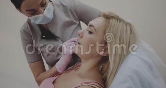美容师为一名女性做唇部注射在电影院的Canera拍摄12位颜色深度视频的预览图