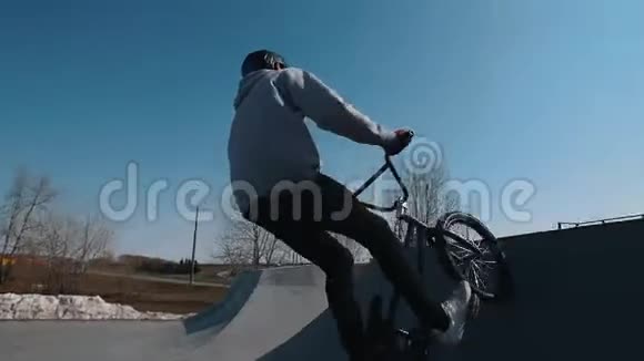 一个骑自行车的人在溜冰场表演魔术在前轮上赛车并保持平衡视频的预览图