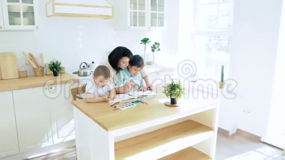 妈妈在厨房里帮两个儿子用纸笔画视频的预览图