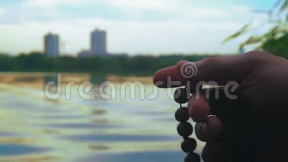 特写镜头男人手里拿着罗莎莉在河岸边读晚祷视频的预览图