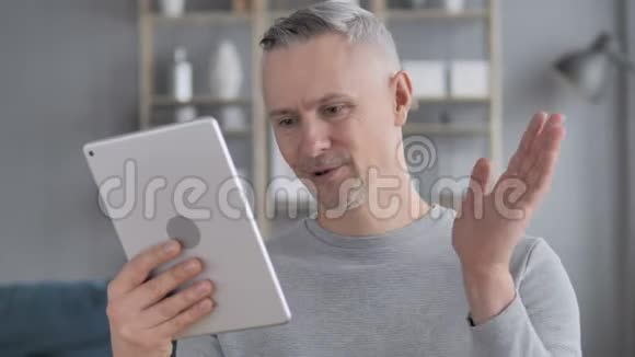 灰发男子在平板电脑上的在线视频聊天视频的预览图