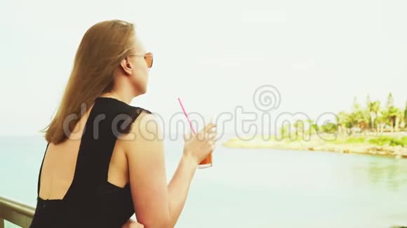 女人喝鸡尾酒在海边放松视频的预览图
