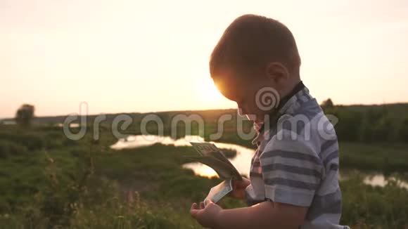 一个可爱的小男孩饶有兴致地看着百元钞票慢吞吞地走着视频的预览图