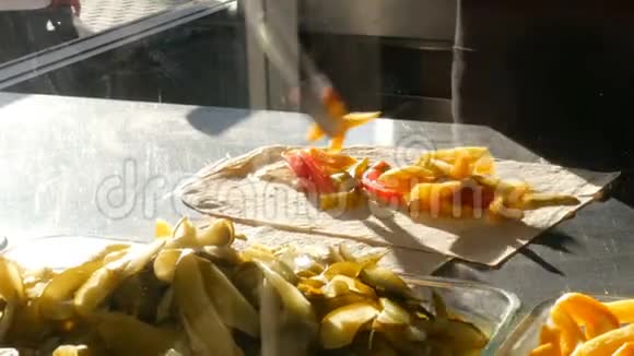 男人做阿拉伯或土耳其沙瓦玛啤酒烤肉串把薯条西红柿黄瓜放在皮塔面包上街头食品脂肪视频的预览图