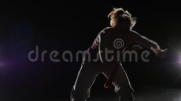 特写舞者在黑暗中练习卡波伊拉对抗聚光灯慢动作视频的预览图