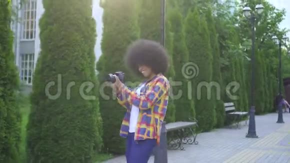 非洲妇女有非洲发型摄影师在城市景观上有相机视频的预览图