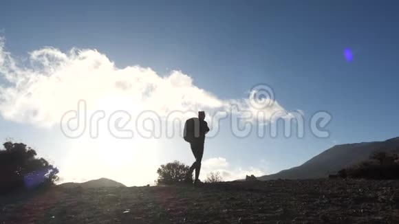 一位年轻女子徒步旅行的剪影背着背包走上山顶迎着蓝天和晚霞视频的预览图