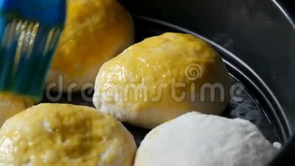 女性面包师用一个鸡蛋将面团中的丸子涂上油脂这样就可以近距离观看自制烘焙片上的烘焙视频的预览图
