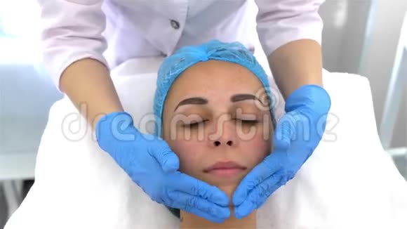 专业美容师和皮肤科医生给一个年轻的女人做面部按摩收紧和恢复活力的程序视频的预览图