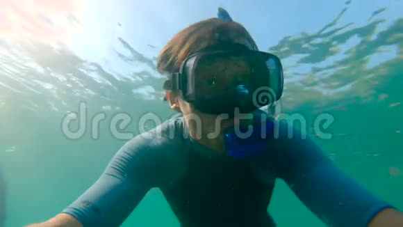 一个年轻人浮潜和潜水潜入海里的慢动作镜头一件衬衫袖子上的UF50表明视频的预览图