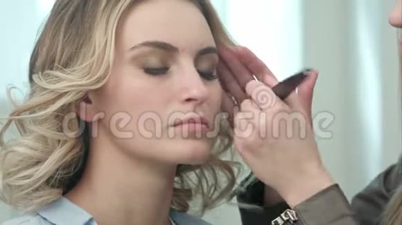 专业化妆师在年轻模特脸上涂粉视频的预览图