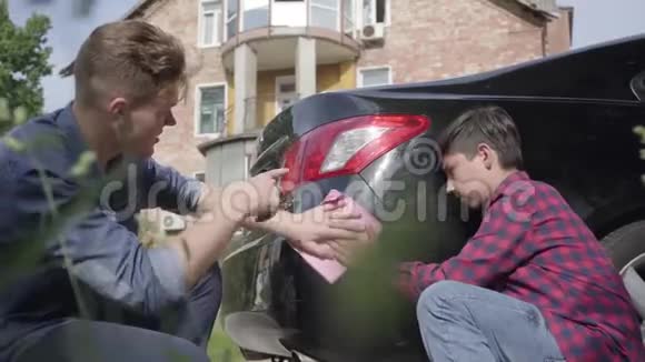 年轻的父亲教儿子爱车那人和一个男孩用抹布近距离擦拭机器男人视频的预览图