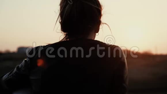 一个年轻女孩坐在一辆运动自行车上欣赏日落的肖像视频的预览图