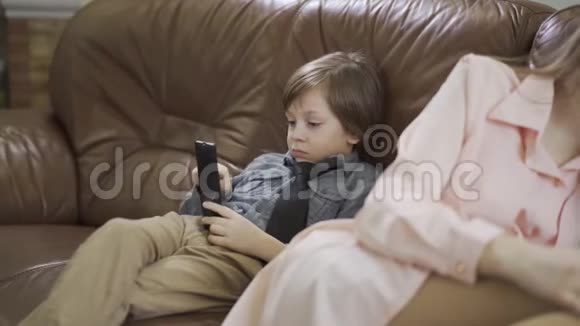 小男孩坐在沙发上在沙发上小妹妹坐在旁边用手机说话视频的预览图
