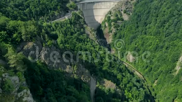 森林覆盖的群山中水力发电大坝的鸟瞰图视频的预览图