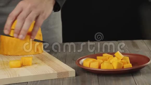 奶油南瓜汤烹饪健康食品厨师把南瓜片放在一张棕色盘子里的木桌上侧视4K视频的预览图
