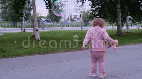 快乐的小女孩在夏天的公园里跑去买肥皂泡快乐的童年概念视频的预览图