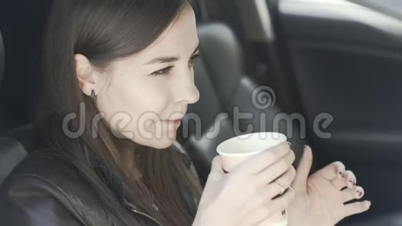 美丽的女人坐在车里喝着咖啡望着窗外微笑视频的预览图