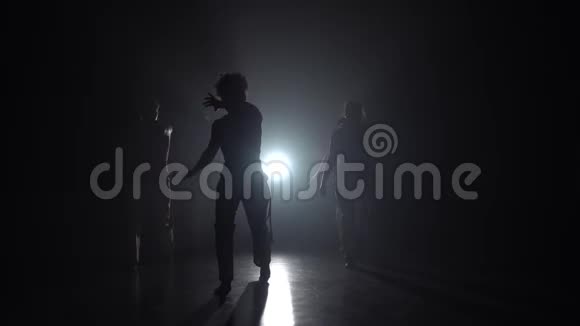 专业舞者在黑暗中练习卡波伊拉对抗演播室的聚光灯视频的预览图