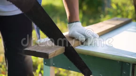 在阳光明媚的后院里工作手套中的贴身木工手锯木板视频的预览图