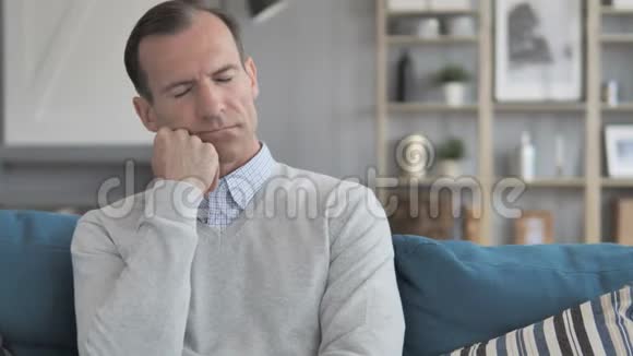 疲惫的中年男人坐在沙发上睡觉视频的预览图