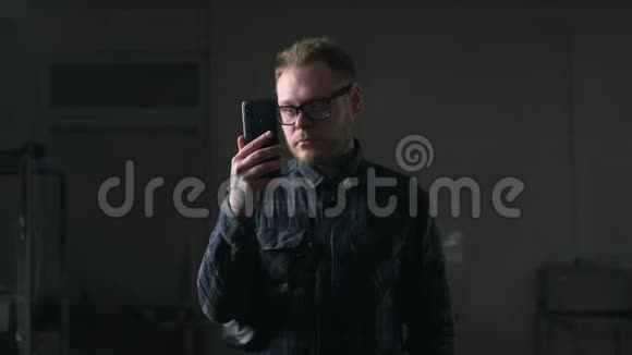 戴眼镜的人在黑暗的环境中看智能手机上的视频戴小玩意的人上网视频的预览图