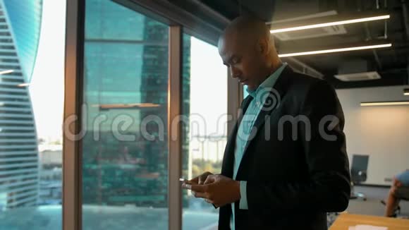 穿着正式服装的非裔美国商人在信使与智能手机聊天视频的预览图
