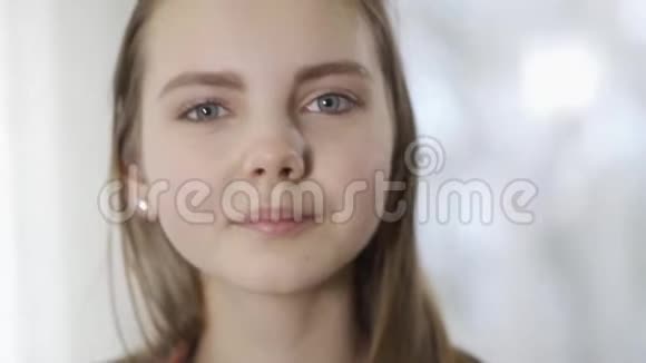 一幅美丽的少年女孩的肖像长发和灰色的大眼睛在镜头中微笑可爱孩子的脸视频的预览图