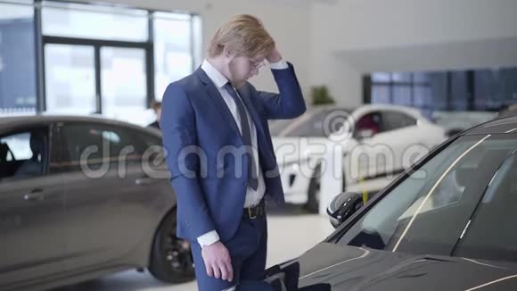 有胡子的商人在经销商中选择汽车在车展上一个高个子男人在汽车旁的头发上手挽手视频的预览图
