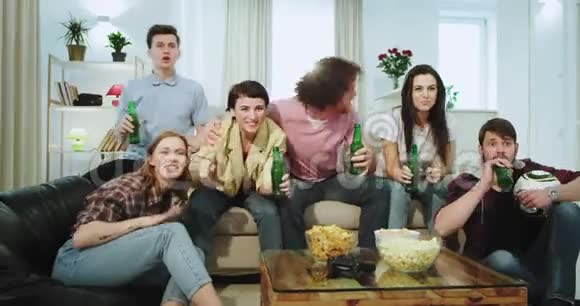特写大公司的朋友多民族在电视机前喝啤酒看他们支持的足球赛视频的预览图